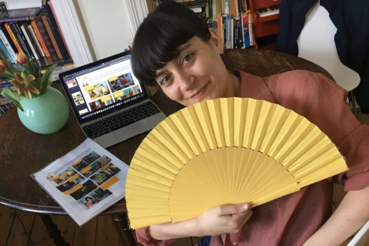 Woman holding fan sitting in front of Battersea Spanish material 